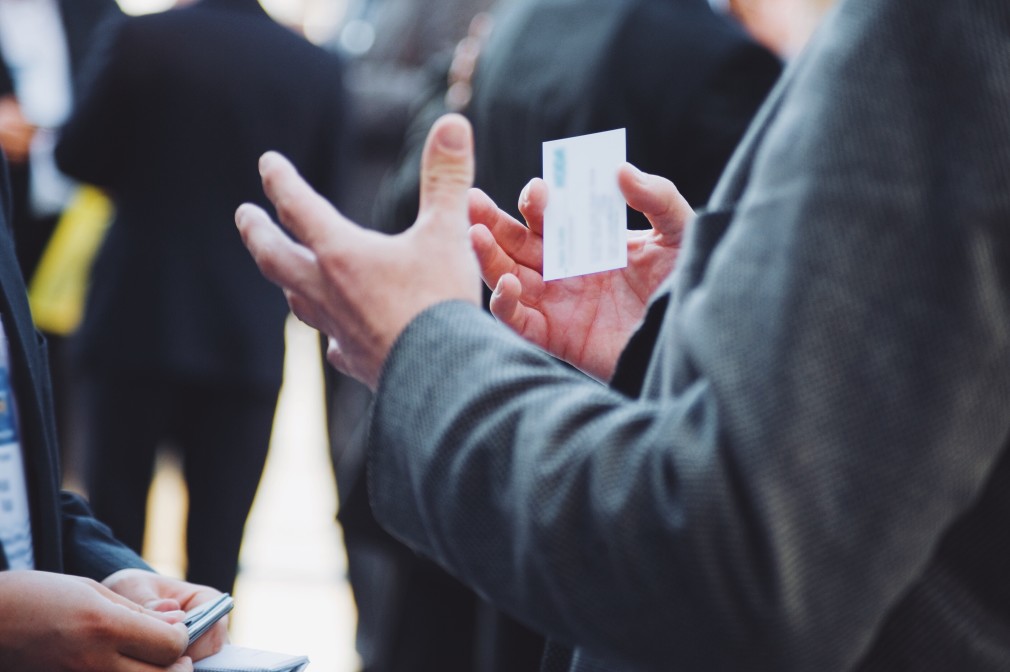 person holding business card ready to hand it out at networking event